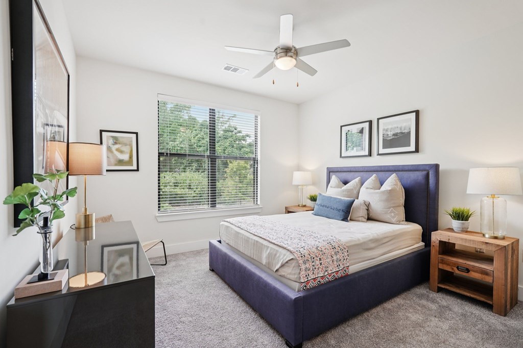 A large bedroom with a window and a ceiling fan.